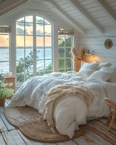 a bedroom with an ocean view is shown in this image, and the bed has white linens on it