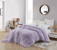 a bed covered in purple fluffy blankets and pillows