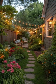 an outdoor patio with lights strung over it and flowers in the foreground, surrounded by greenery