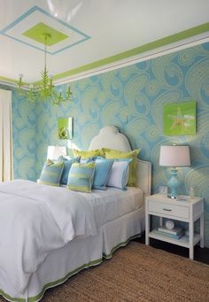 a bedroom with blue and green wallpaper, white bedding and two nightstands