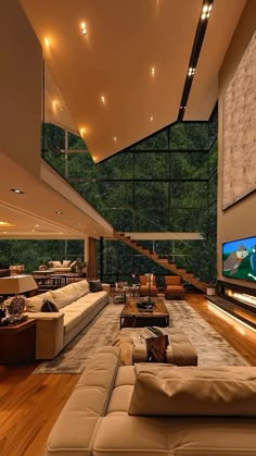 a large living room with couches and a television in the center, along with stairs leading up to an upper floor