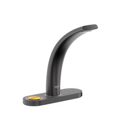 a black faucet that is on top of a white wall with a yellow light