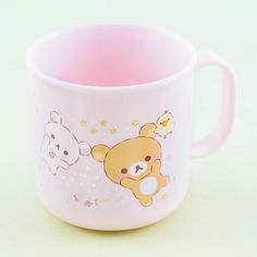 a pink coffee mug with a teddy bear and chick on the front, sitting on a white surface