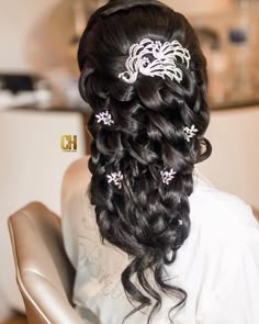 a woman is sitting in a chair with her hair styled into a half updo