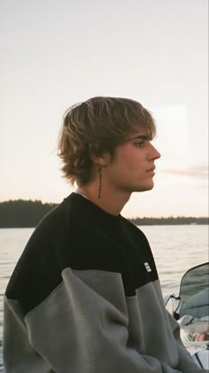 a young man sitting on top of a boat in the water