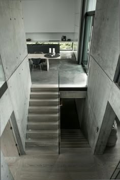 an open door leading to a living room and dining area in a concrete building with stairs