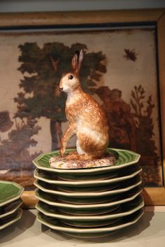 a rabbit figurine sitting on top of stack of plates