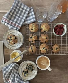 muffins and berries on a cooling rack next to cups of coffee, water and fruit