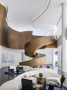 an elegant living room with modern furniture and large spiral staircase