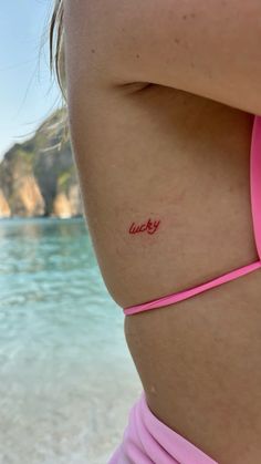 a woman with a tattoo on her back showing the word lucky written in red ink