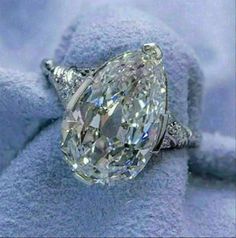 an oval cut diamond ring sitting on top of a blue blanket