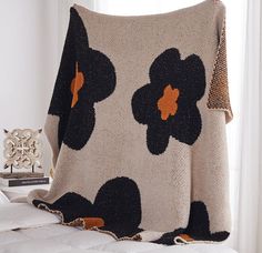 a black and white flowered blanket sitting on top of a bed next to a window