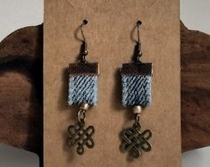 the earrings are made from woven material and have metal hooks on them, with an intricate design