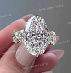 an oval diamond ring with three pear shaped diamonds on the sides and four clawed shoulders