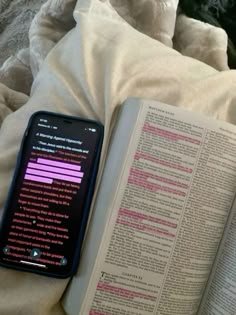 an open book and cell phone on a bed