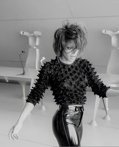 a black and white photo of a woman with her hair in high buns wearing leather pants