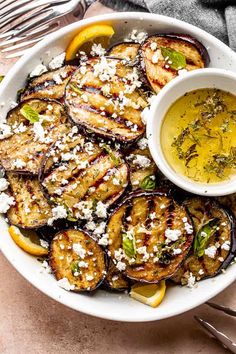 grilled eggplant with lemon and feta cheese in a white bowl on a table