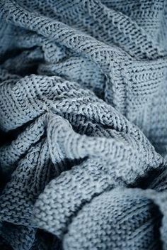 a pile of gray knitted blankets sitting next to each other