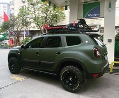 a green car parked in front of a gas station with its roof rack on top