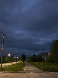 an empty street at night with dark clouds