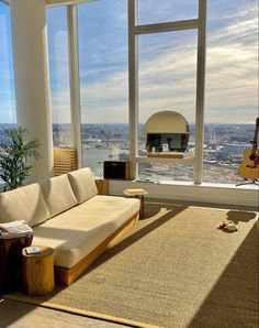 a living room filled with furniture and large windows overlooking the cityscape in the distance