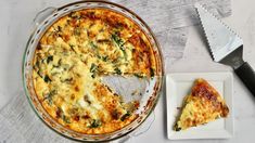 a cheesy quiche on a plate with a slice missing from it next to a spatula