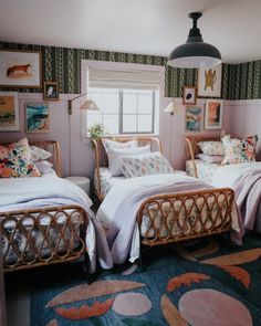 two twin beds in a room with pictures on the wall and rugs around them