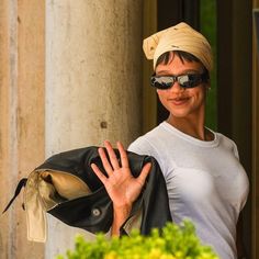 a woman wearing sunglasses and a turban is holding her hand out to the side