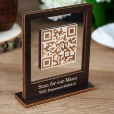 a wooden block with a qr code on it sitting on a table next to flowers