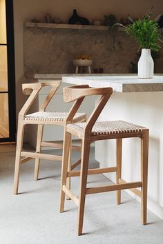 two wooden stools sitting next to each other in a kitchen with white counter tops