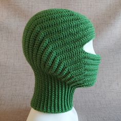 a green knitted hat sitting on top of a white mannequin's head