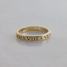 This is a personalized Roman Numeral band in solid 14K gold. The date of your choice is written in Roman Numerals twice around the ring(with a dot separator in between them) Features of the ring:   -Date of your choice is written twice around the band. Or instead, you can choose two  different dates.   -Font is Times New Roman, which is cast right into the ring to give the letters plenty of depth   -Band is 3mm wide and 1.5mm thick.    -Made to order in your size.  - Arrives in a rectangular bla 14k Yellow Gold Bands As Gift, Timeless Gold Bands Stamped 14k, Personalized Engraved 14k Gold Ring, Gold Engraved Promise Band, Classic Engraved Band As Gift, Timeless Yellow Gold Bands As Gift, Gold Engraved Stackable Heirloom Rings, Classic 14k Gold Personalized Stackable Rings, Timeless Gold Engraved Ring With Engraving Option