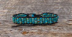 Measures: 9" Can be adjusted down to about 7" Width: 5/8" Weight: 10 grams Want a unique accessory to brighten your day? This Turquoise bracelet is handcrafted with delicate beadwork that has been strung together with leather into an array of blue shades to create a design that will be sure to flatter the wrist. This is an item that will certainly be cherished and appreciated by anyone who treasures handcrafted jewelry! Adjustable Turquoise Hand-strung Beaded Bracelets, Adjustable Hand-strung Turquoise Beaded Bracelets, Adjustable Beaded Turquoise Friendship Bracelets, Adjustable Beaded Turquoise Wrap Bracelet, Adjustable Turquoise Wrap Bracelet For Festival, Artisan Blue Adjustable Wrap Bracelet, Adjustable Turquoise Hand-strung Friendship Bracelets, Handmade Turquoise Leather Bracelet Spiritual, Adjustable Hand-strung Turquoise Friendship Bracelets