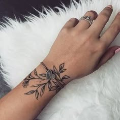 a woman's hand with a flower tattoo on her left wrist and the other arm