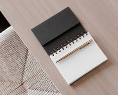 a notepad and pen sitting on top of a wooden table next to a chair