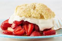 a dessert with strawberries and whipped cream on a blue plate next to a fork