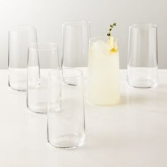 several glasses are lined up next to each other on a table with a drink in the middle