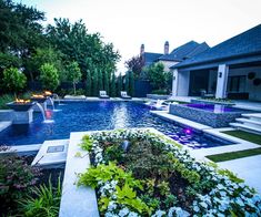 a backyard with a swimming pool surrounded by greenery and flowers in the foreground