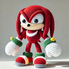 a crocheted sonic the hedge doll is posed on a white surface with one leg up