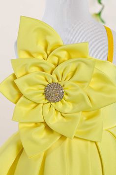 a yellow flower on the back of a dress with gold sequins and beads