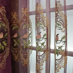 the curtains are decorated with flowers and birds in gold, pink and purple colors on them