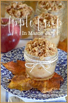 an apple crisp in mason jars on a plate with autumn leaves and apples behind it