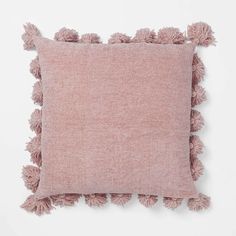 a pink pillow with tasselled edges and a light pink cushion cover on top