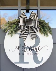 a welcome to our home sign hanging on the front door with a bow and wreath