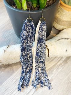 two pairs of blue and white fabric earrings sitting next to a potted plant