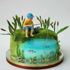 a cake decorated with a boy fishing on the lake and fish in the pond,