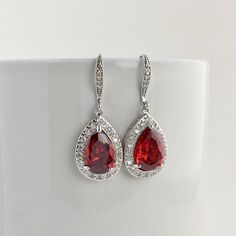 I've created these gorgeous red ruby cubic zirconia bridal tear drop dangle earrings in rhodium plated brass setting. Earrings feature a large teardrop with pear cut red ruby cubic zirconia center surrounded by tiny round zirconia crystals. Teardrop dangles from a cubic zirconia detailed ear wire. Total length of the earring is 3.8 cms. For matching necklace click: https://www.etsy.com/listing/469844682/red-ruby-cubic-zirconia-teardrop-bridal?ref=shop_home_active_26 For matching bracelet click: Red Wedding Jewelry, Red Crystal Jewelry, Jewelry Set Red, Bridesmaid Jewelry Set, Red Bridesmaid, Red Bridesmaids, Cubic Zirconia Bracelet, Ruby Wedding, Wedding Jewelry Set