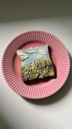 a pink plate with a piece of bread on it sitting on top of a table