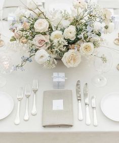 a table set with silverware and white flowers