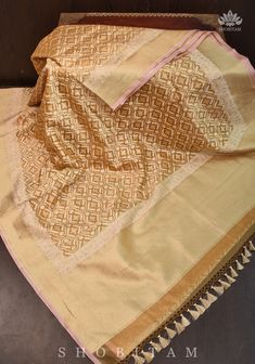 This Saree is an ode to the rich design traditions of Banaras. It is set in an elegant and earthly beige hue. The fine body of the saree features delicately woven motifs in atrellis jaal . This is complimented perfectly by the grand pallu. The base material used to craft the saree is kora or pure silk organza and tissue. In addition to this, we have incorporated designer tassels on the sarees to elevate its charm.   SILK MARK CERTIFIED This saree is ready to wear with fall and pico done. Handmade silk tassels adorn the pallu and add more grace to it. An unstitched blouse fabric is included. *Note: There may be minor variations in the shade, the texture of the product. Hues/textures show differently due to variations in screen settings and other factors, *Note: This is a handwoven saree and Gold Raw Silk Pre-draped Saree For Festivals, Traditional Gold Pre-draped Saree For Navratri, Semi-stitched Gold Banarasi Silk Traditional Wear, Gold Handloom Dola Silk Pre-draped Saree, Traditional Beige Chanderi Sharara, Traditional Drape Beige Chanderi Sharara, Beige Chanderi Sharara With Traditional Drape, Cream Designer Dupatta With Traditional Drape, Designer Cream Dupatta With Traditional Drape